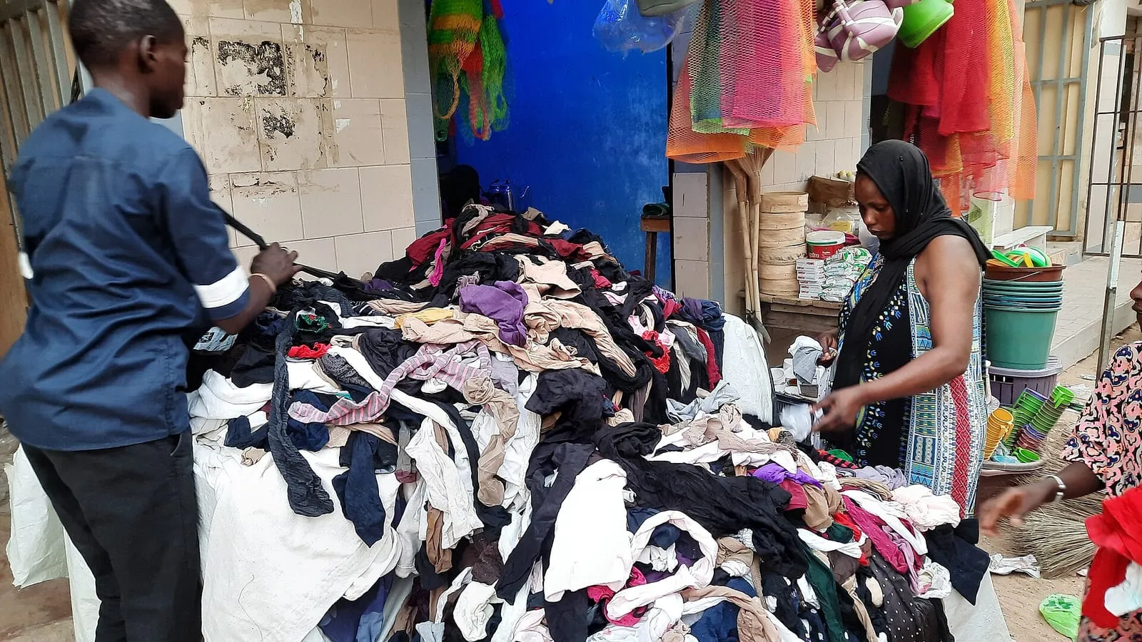 Un vendeur présente des vêtements de seconde main dans une boutique de friperie