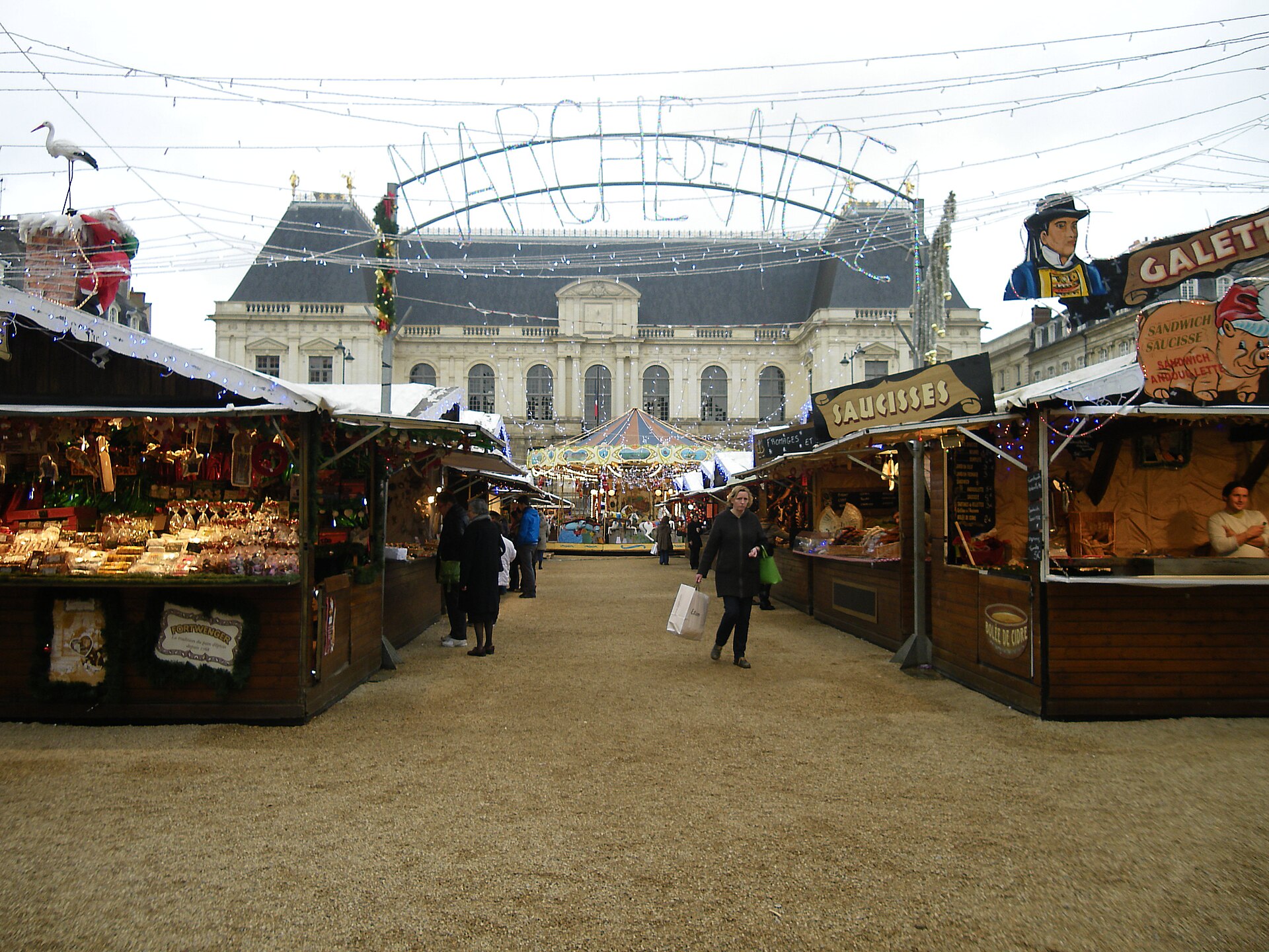 Chalets d'un marché de Noël illuminé, sous les décorations de fin d'année